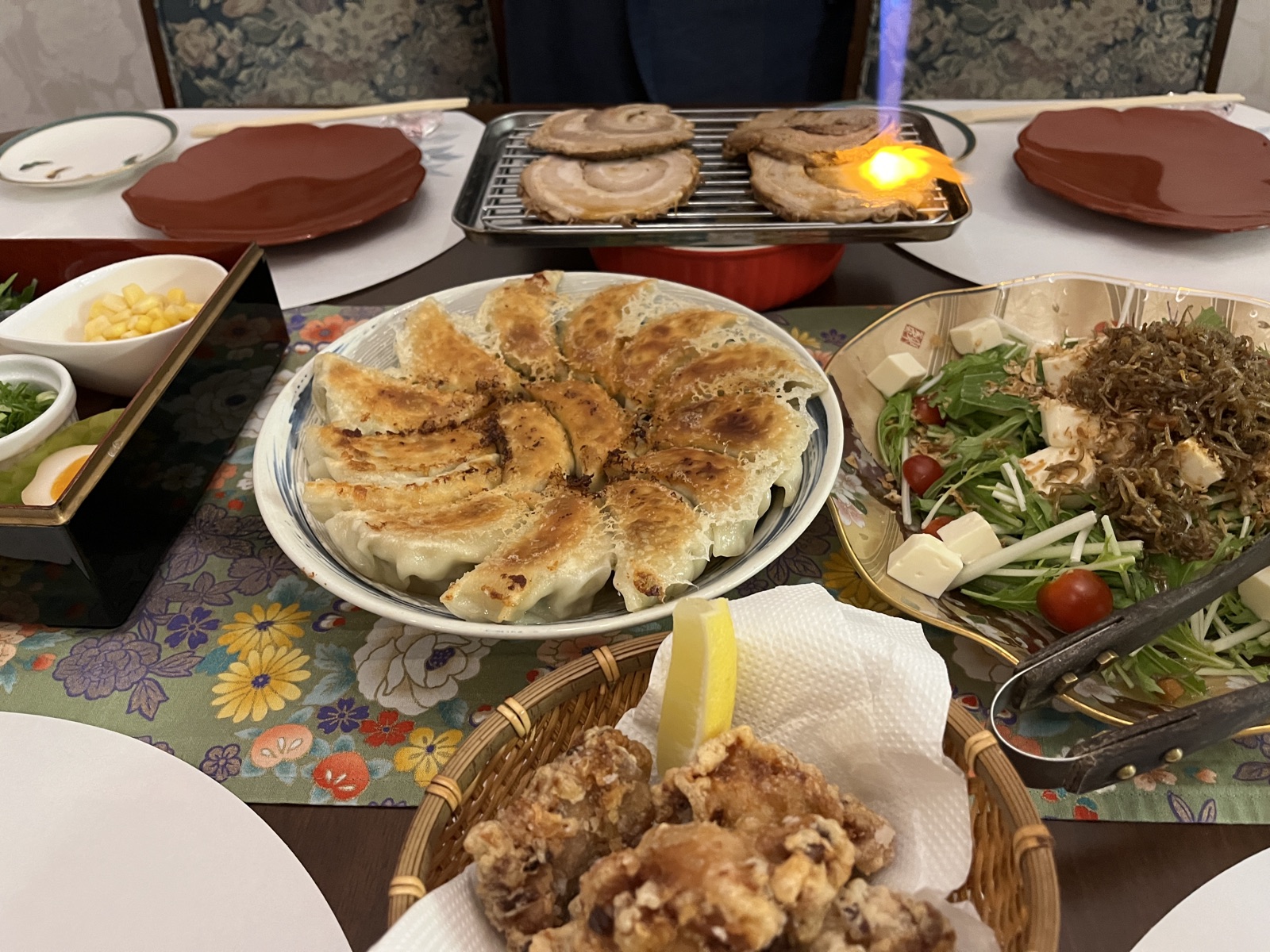 The dinner table: hand-folded gyoza, salad with crispy sardines and tofu, karaage, and chashu being torched