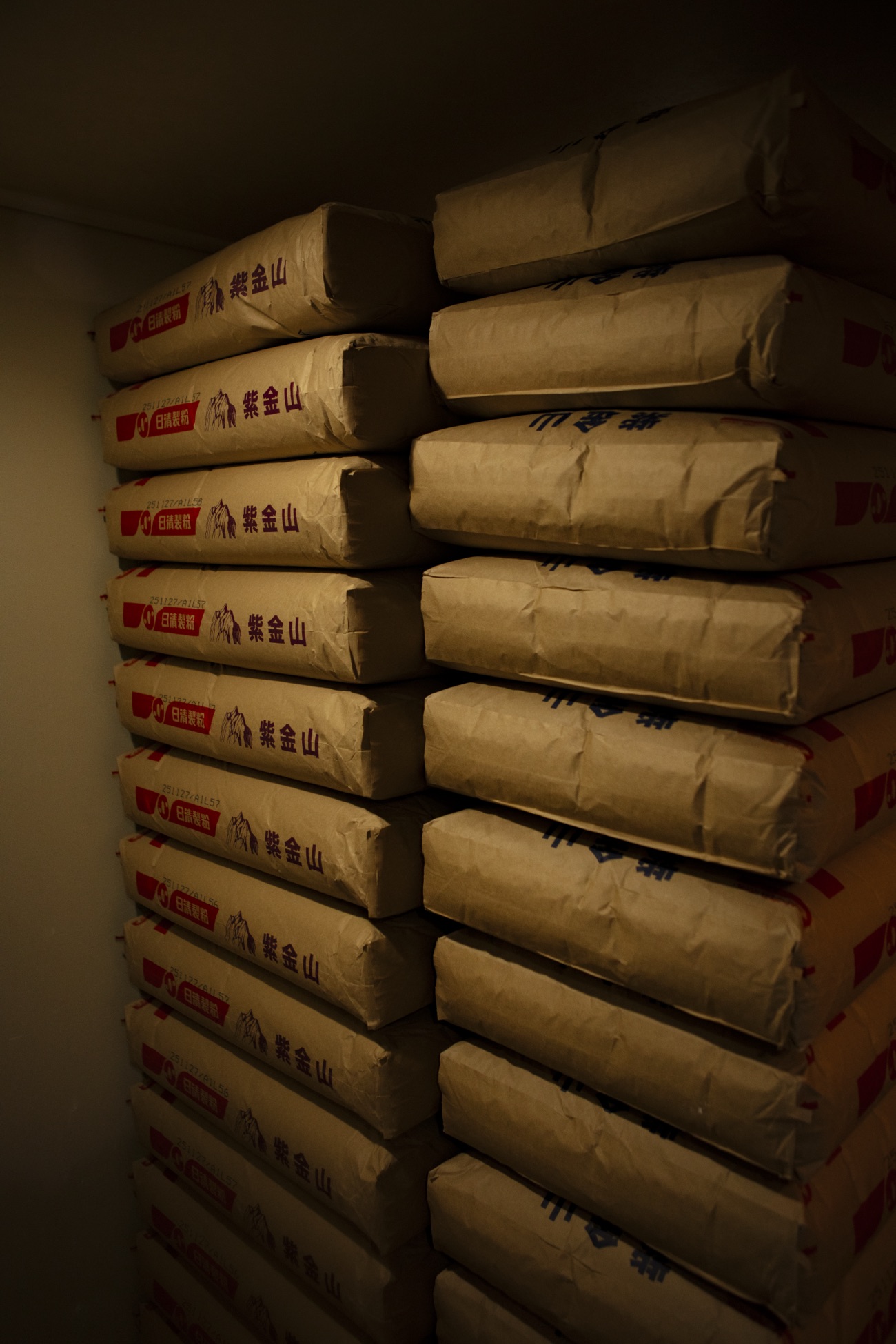 Bags of noodle flour stacked high inside the factory